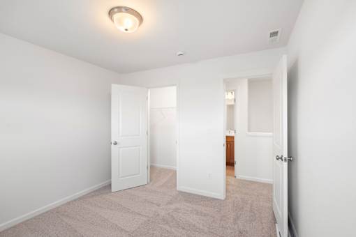 Room with white walls and carpeted floor with two open doors.