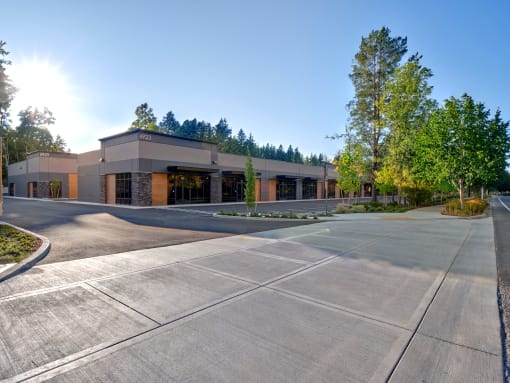 an empty parking lot in front of a building with trees