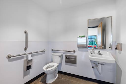 A white toilet with a white sink and a mirror in a bathroom.