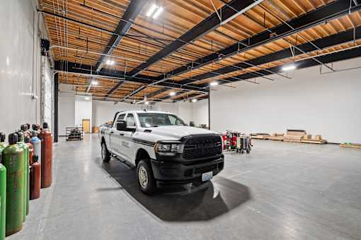 A white truck is parked in a large, empty warehouse.