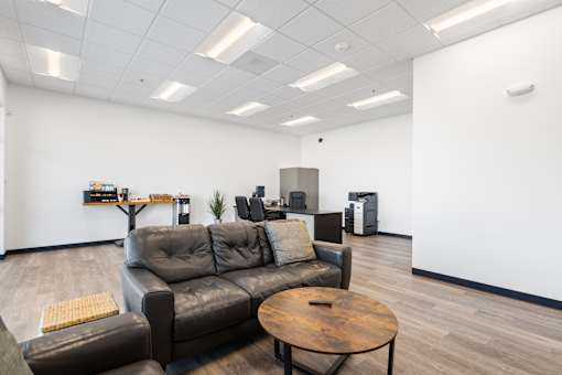 A modern office space with a couch, chair, and a table.