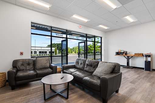 A black leather sofa and chair in a room with a glass door.