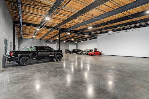 A black truck is parked in a large, empty garage.