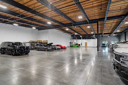 A spacious garage with a black car in the foreground.
