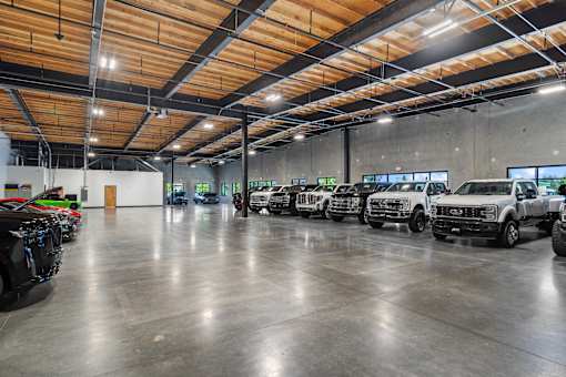 A row of black and green cars are parked in a large garage.