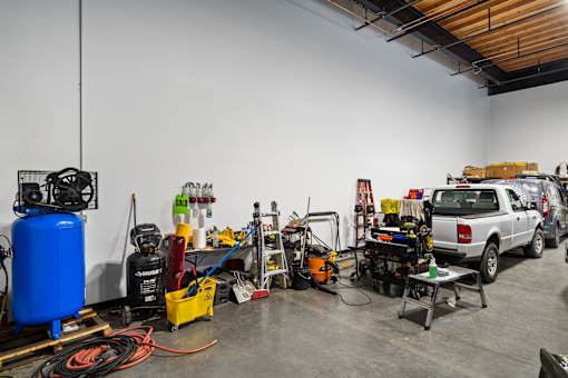 A room with a white wall and a blue air compressor.