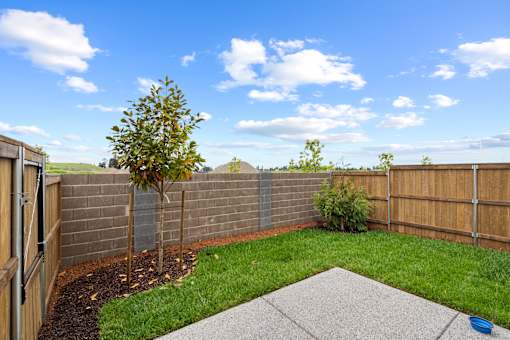 A backyard with a fence, a tree, and a concrete slab.