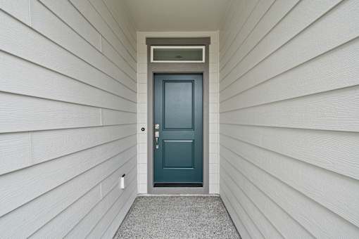 A white house with a blue door and a grey mat.