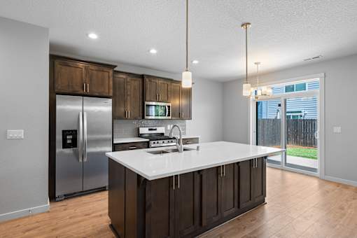 A modern kitchen with dark wood cabinets and stainless steel appliances.