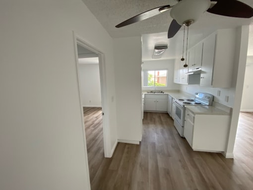 an empty kitchen with white cabinets and a wood floor