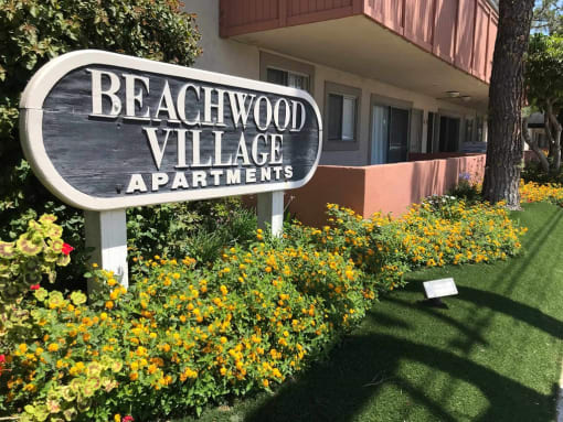 a sign apartments in front of flowers