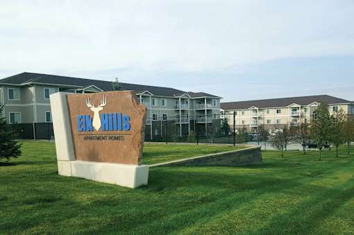 A sign for Eco Hills Apartment Homes sits in front of apartment buildings.
