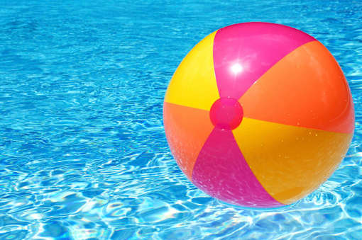 A colorful beach ball floating in a pool of water.