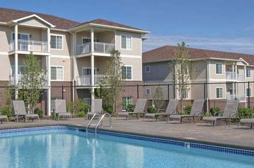 A swimming pool is in front of apartment buildings.