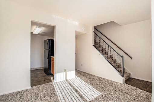 A room with a staircase and a refrigerator.