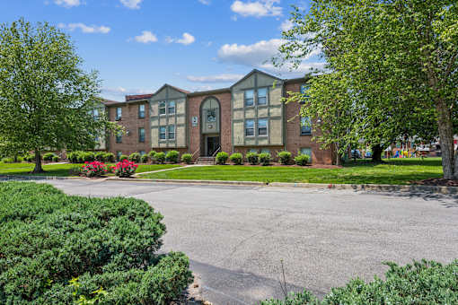 A large building with a red brick facade and a green lawn in front.