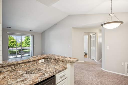 A kitchen with granite countertops and a large window.