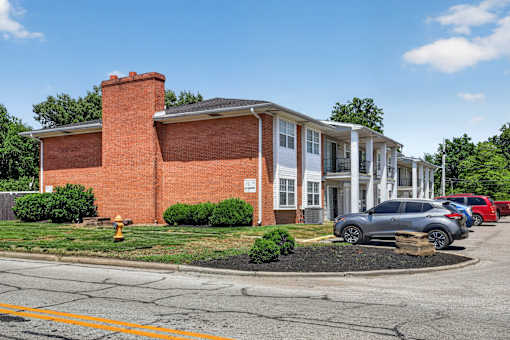 A red brick building with a white garage door and a grey car parked in front.