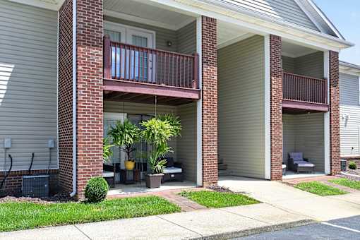 A red brick house with a balcony and a small garden.