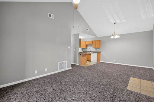 A room with a kitchenette and a carpeted floor.