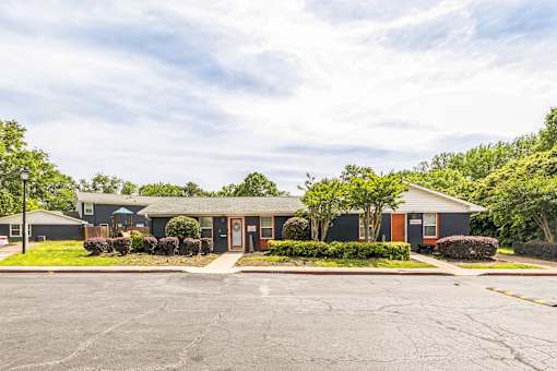 A parking lot in front of a building with trees and bushes.