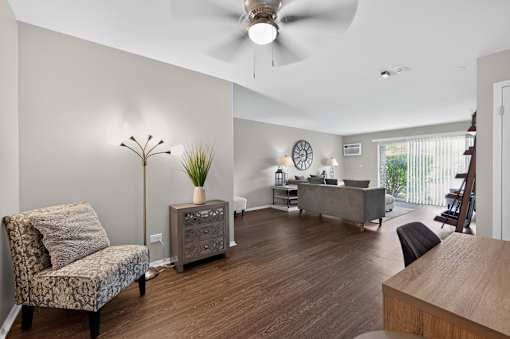 Living room at Renaissance at Carol Stream featuring a chair, plant, and ceiling fan in Carol Stream, IL.