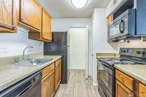 Kitchen with wood cabinets and black appliances at Ashford Place Mobile AL