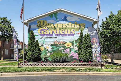 A large sign for Devonshire Gardens Apartments is displayed in front of a building.