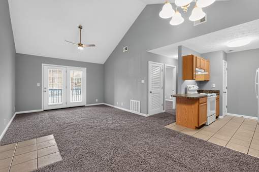 A spacious living room with a kitchenette and a ceiling fan.