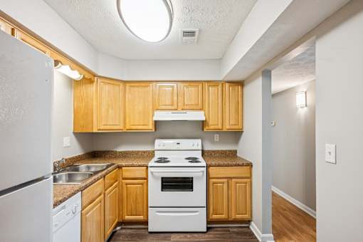 A kitchen with wooden cabinets and a white stove top oven.