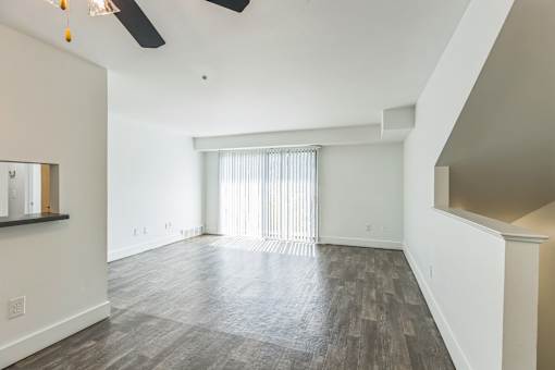 A spacious room with a ceiling fan and wood flooring.
