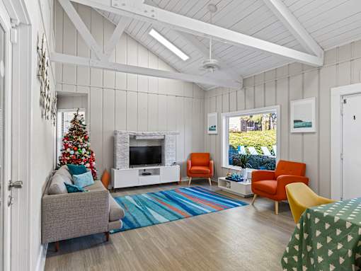A living room with a grey couch, a Christmas tree, and a fireplace.