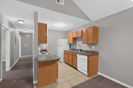 A kitchen with a white dishwasher and wooden cabinets.