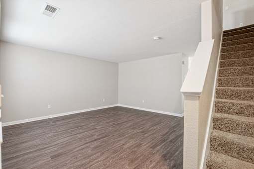 A room with a staircase and wooden flooring.