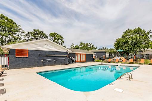 A swimming pool in a backyard with a building in the background.