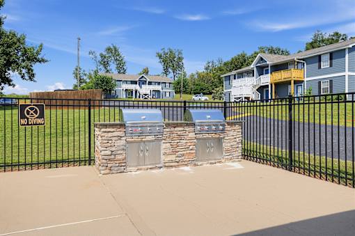 A black fence with a sign that says "No Diving" in front of a stone wall and a blue grill.