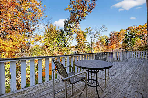 A wooden deck with a table and a chair overlooking a forest.