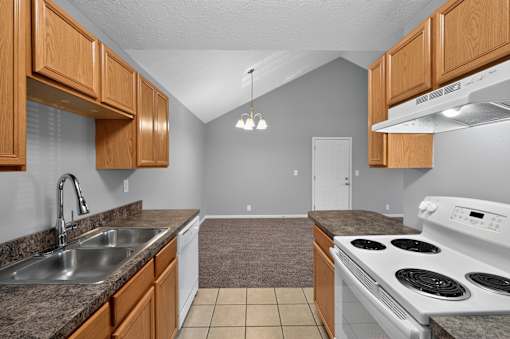 A kitchen with a stove, sink, and cabinets.