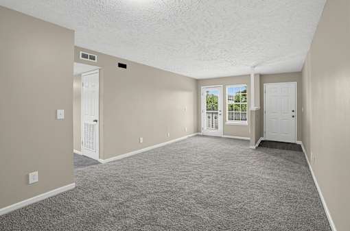 Spacious foyer and living room with carpeted floor and white walls at Arbours at Victoria Place in Prattville, AL