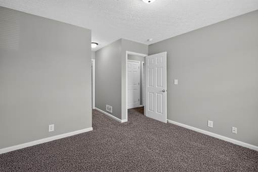 A room with a carpeted floor and a white door.