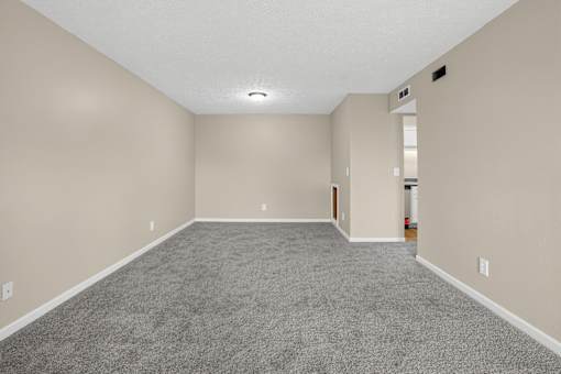 Large empty dining room with carpeted floor and white walls at Arbours at Victoria Place in Prattville, AL