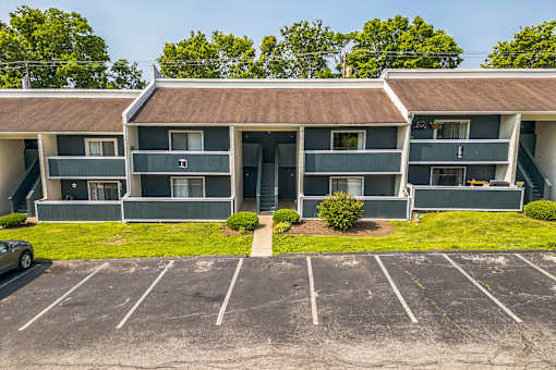 A parking lot in front of a two-story apartment building.