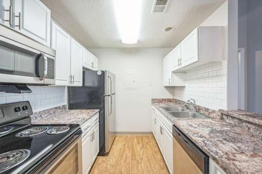A kitchen with black appliances and white cabinets.