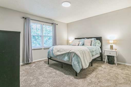 A bedroom with a bed, nightstand, and window.