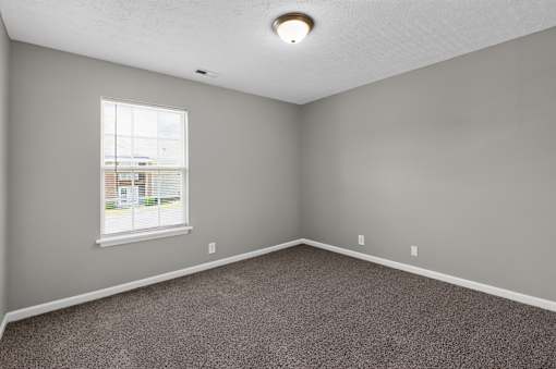 A room with a carpeted floor and a window.