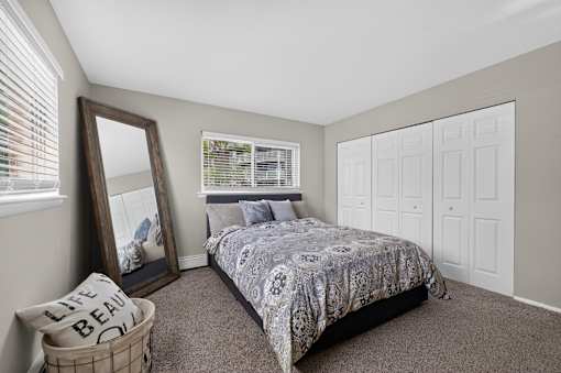 Bedroom at Renaissance at Carol Stream featuring a large bed and wall mirror in Carol Stream, IL.