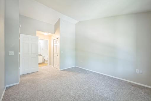 A spacious room with carpeted flooring and white walls.