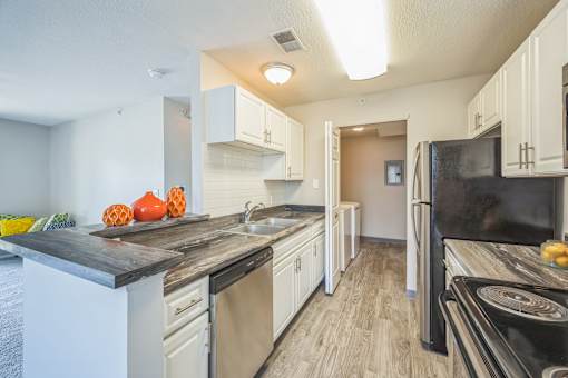A kitchen with black appliances and white cabinets.