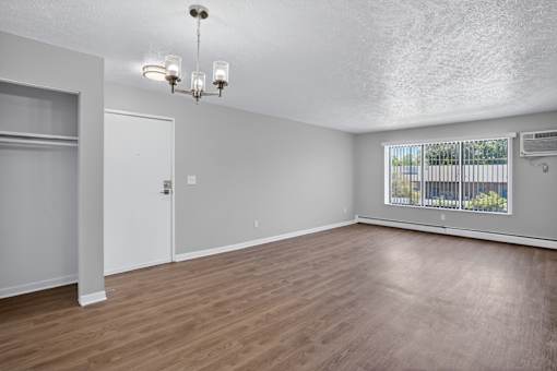 A room with a door and a window with a view of a fence and trees.