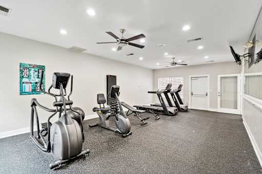 A room with a grey carpet and a wall with a painting and a fan.